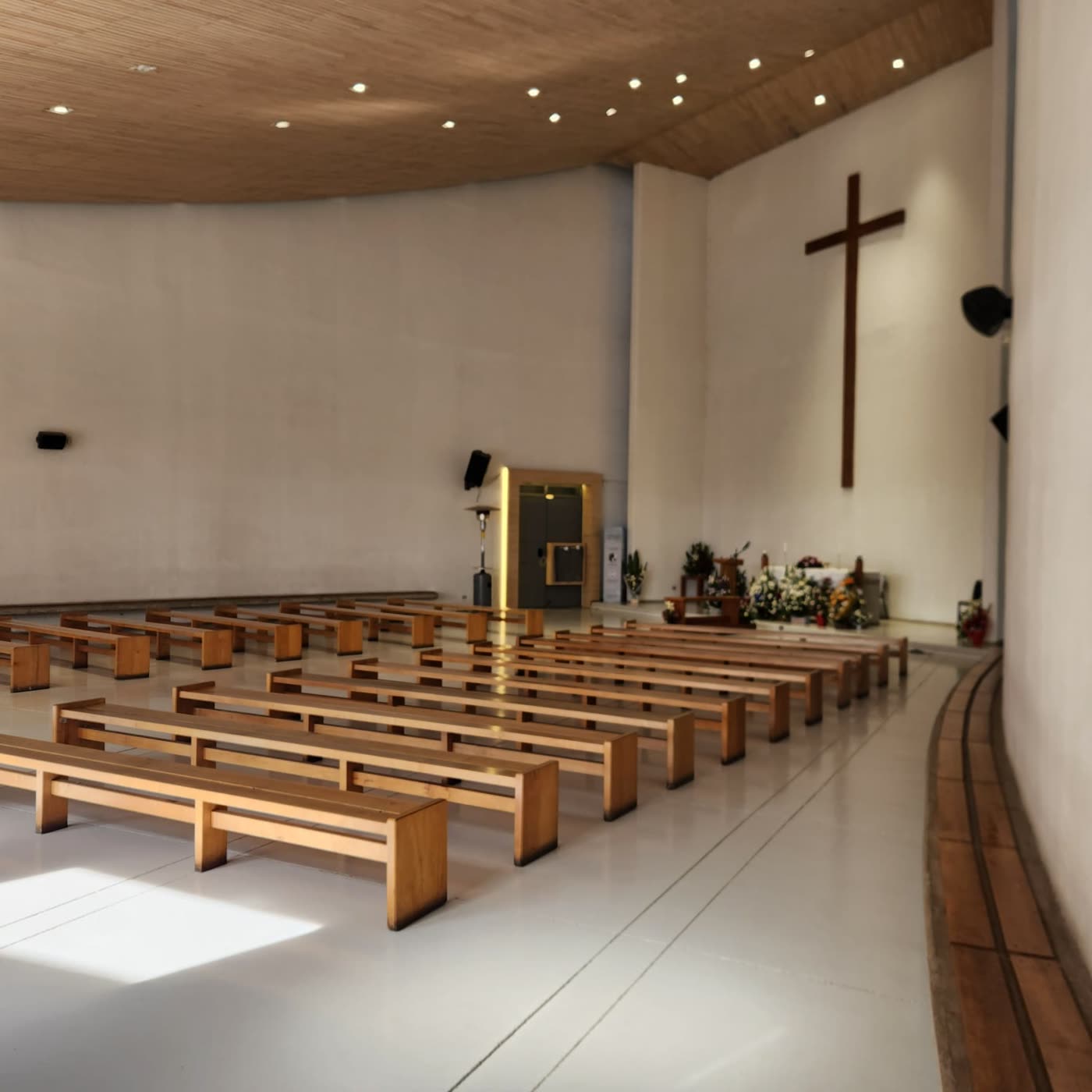 Nave de capilla con bancas de madera, altar y cruz